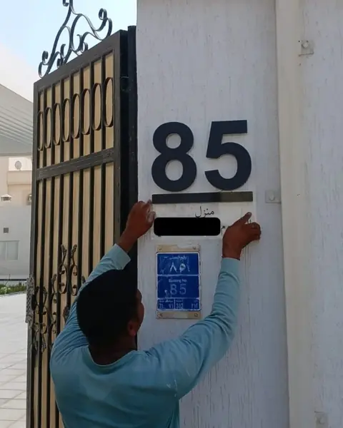فني يركب لوحة رقم بيت